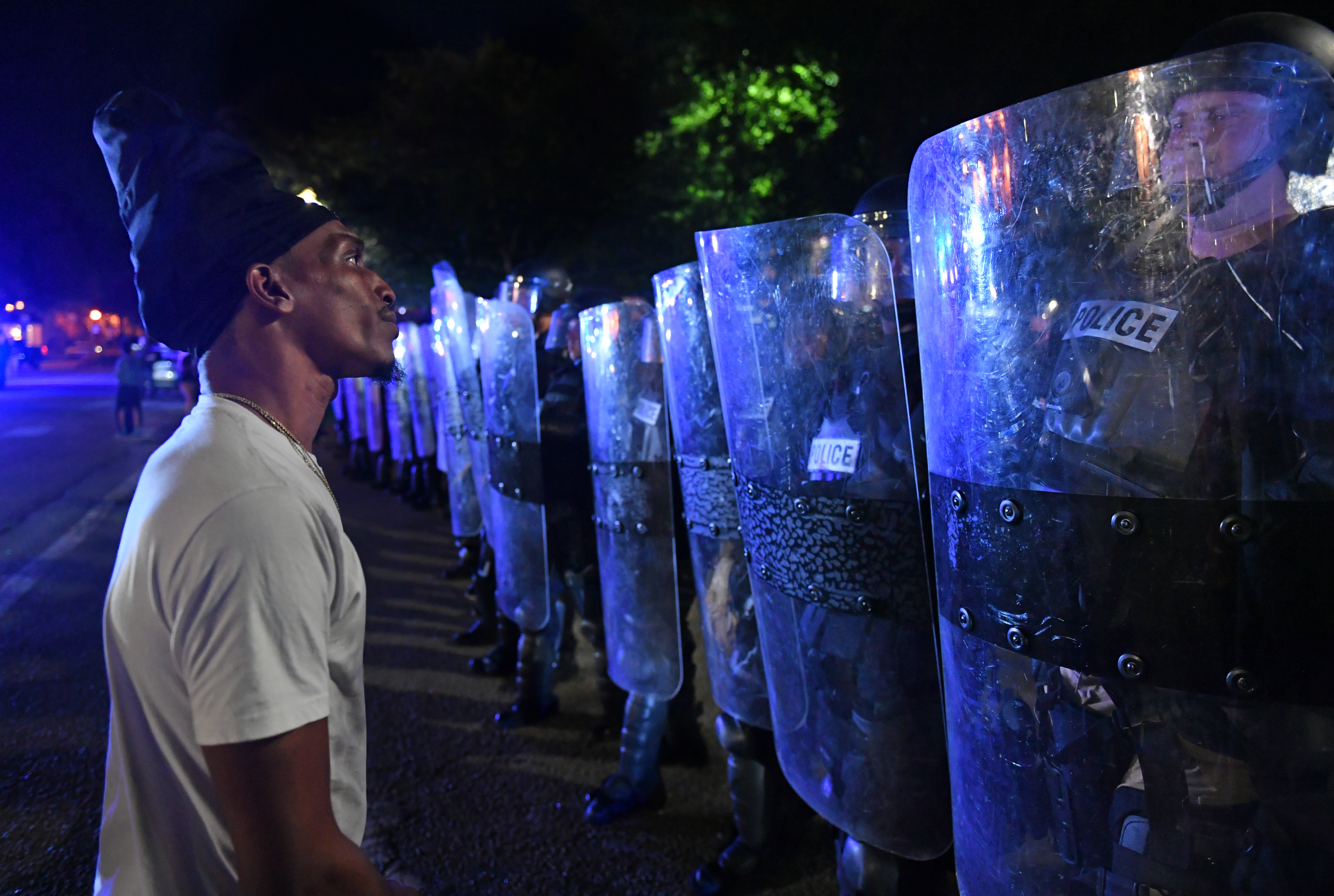 A man faces a row of police officers holding shields.
