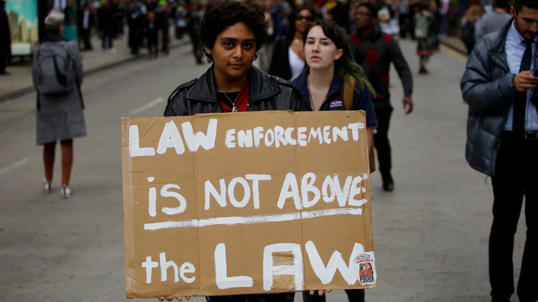 Demonstrator holding a sign reading "Law enforcement is not above the law"