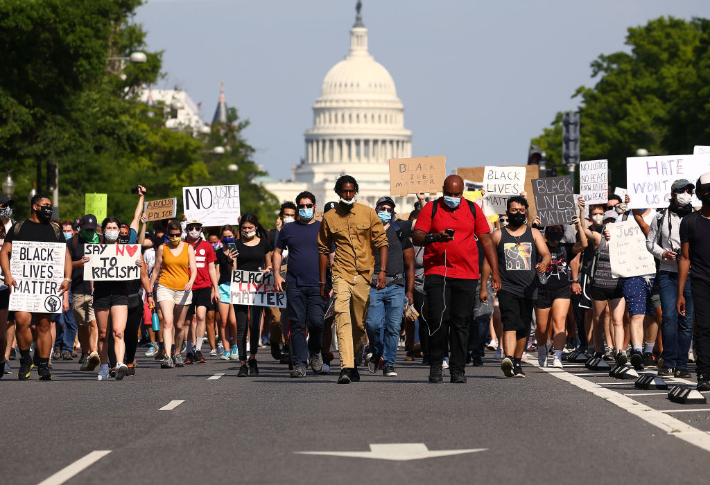 Protestors carrying racial justice signs march away from the U.S. Capitol Building.