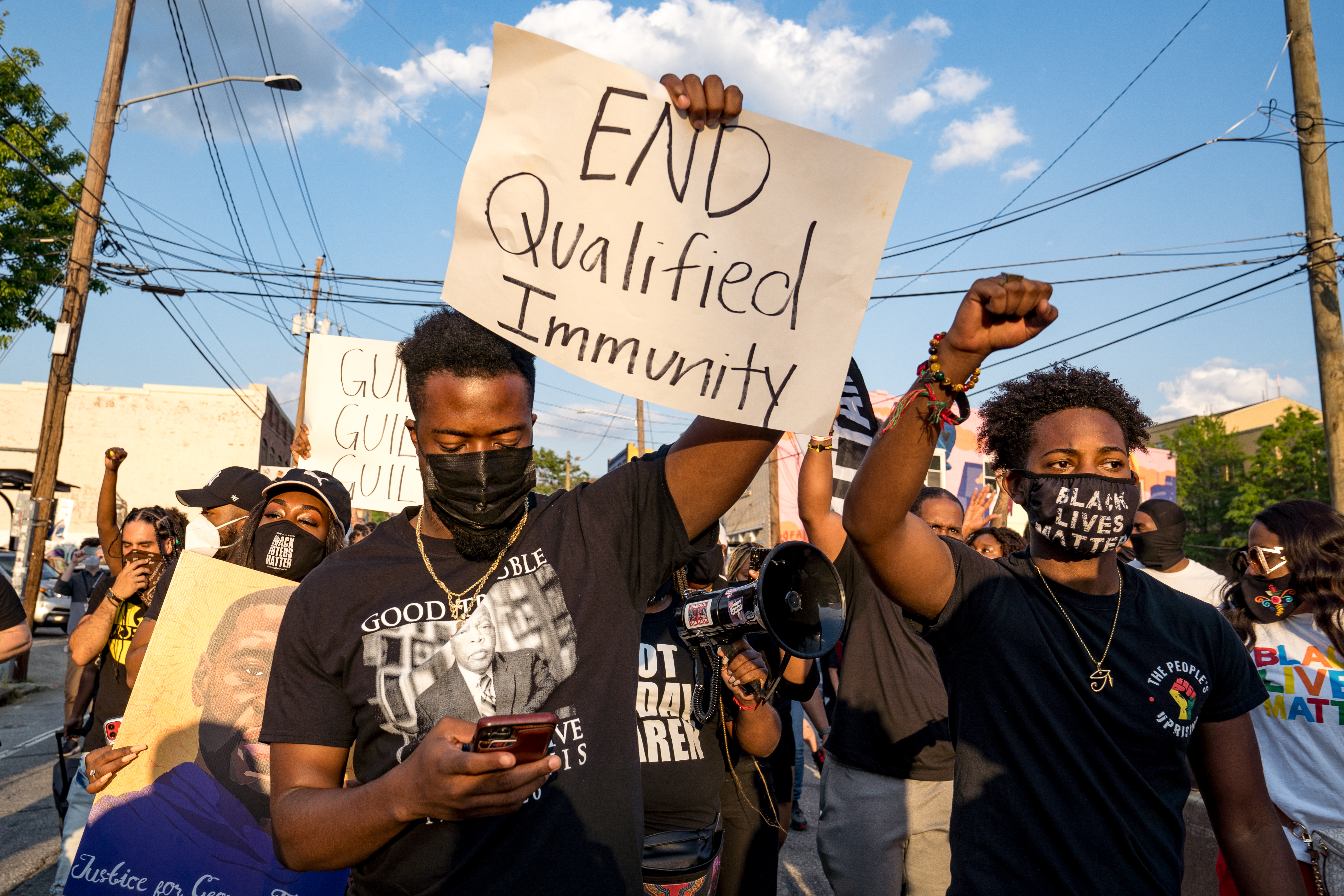 A protestor holds a sign reading "End qualified immunity" 